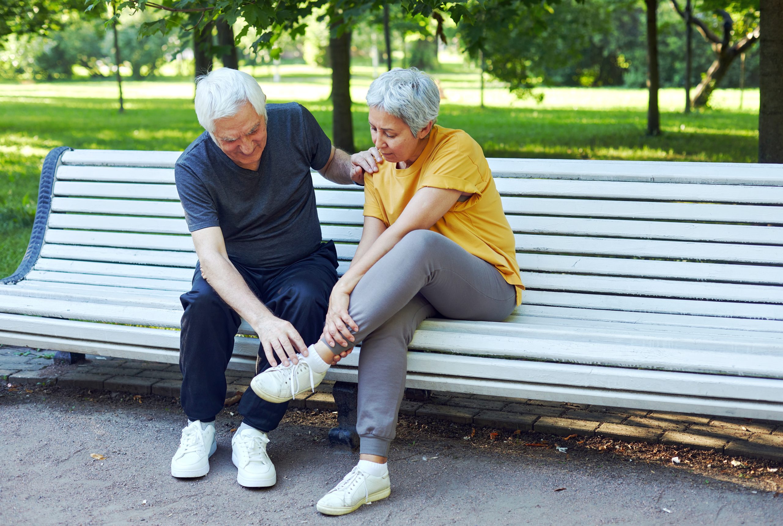 elderly couple sitting in a park with ankle pain